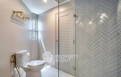 Modern bathroom with elegant herringbone tile and sleek fixtures.