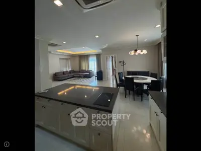 Spacious open-plan living and dining area with modern kitchen in luxury apartment.