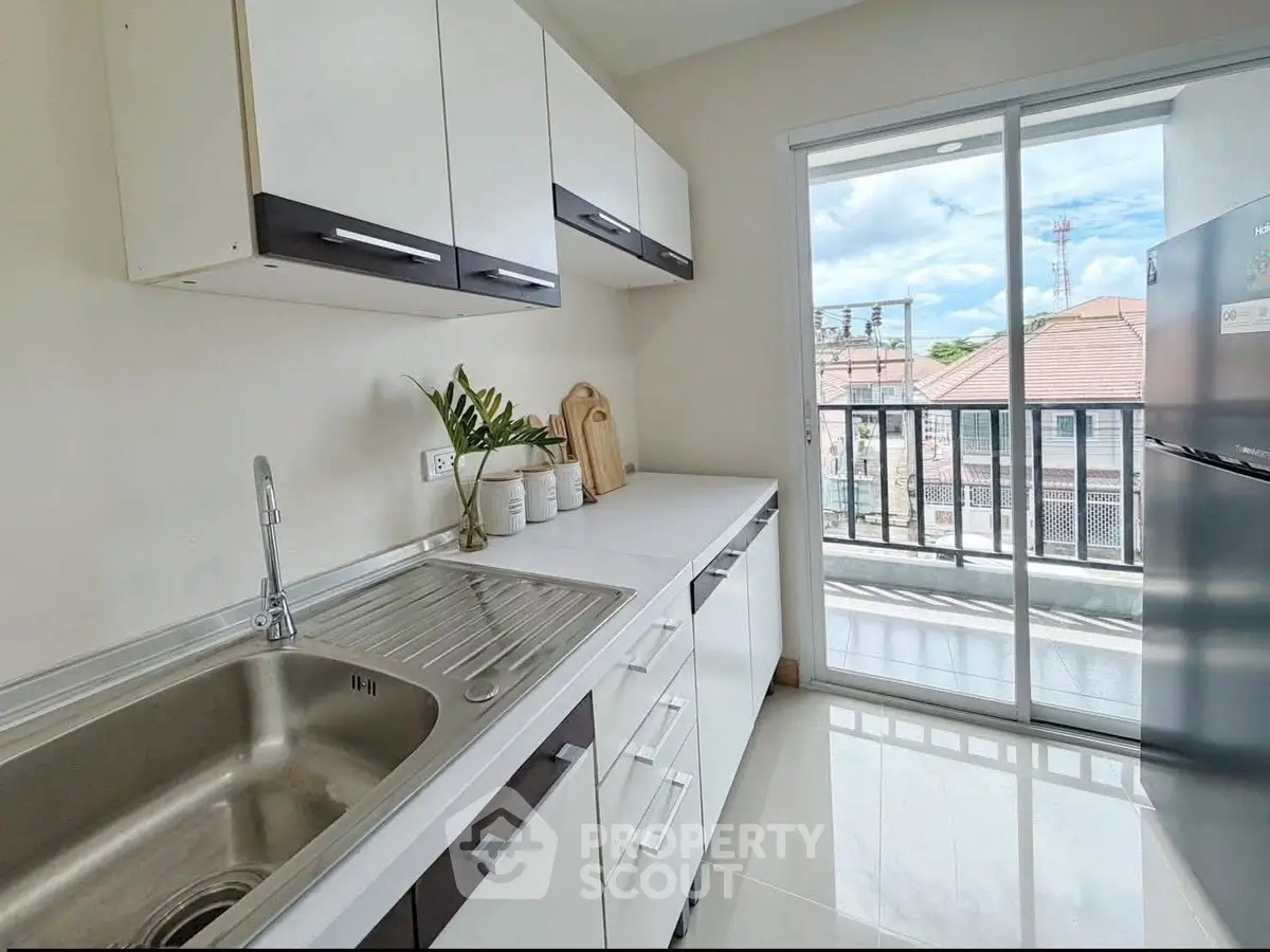 Modern kitchen with sleek cabinets and balcony view in a bright apartment.