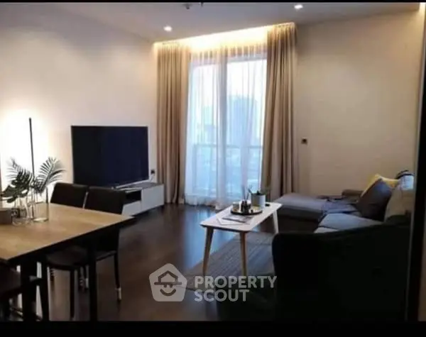 Modern living room with large TV, cozy seating, and elegant decor.