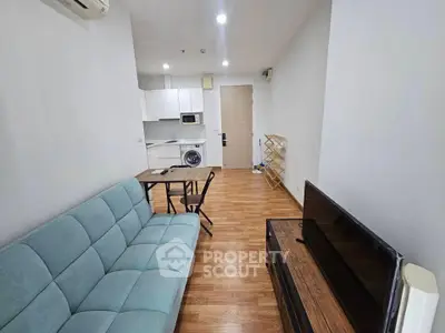Modern living room with open kitchen, featuring sleek furniture and wooden flooring.