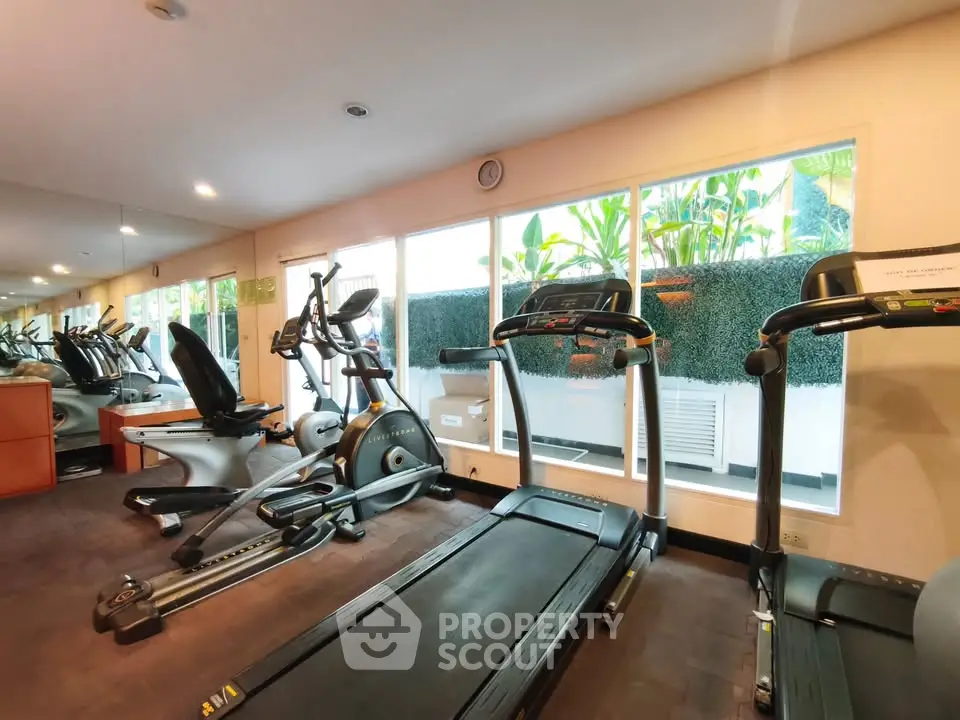 Modern gym with state-of-the-art equipment and large windows for natural light.