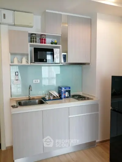 Modern compact kitchen with sleek cabinetry and built-in appliances in a stylish apartment.