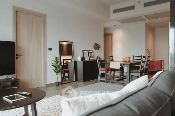 Modern living room with stylish furniture and dining area in open layout apartment.