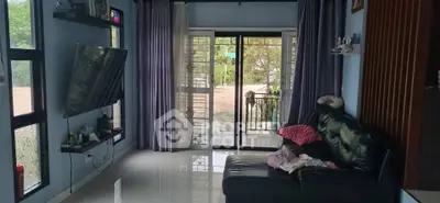 Cozy living room with large windows and balcony access, featuring modern decor and natural light.
