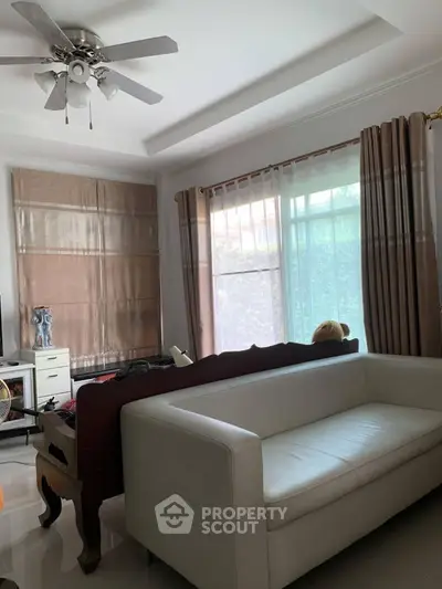 Cozy living room with white sofa and ceiling fan, perfect for relaxation.