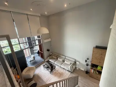 Spacious modern living room with high ceiling and balcony view