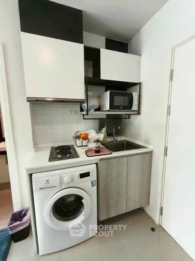 Compact modern kitchen with washing machine and microwave in small apartment