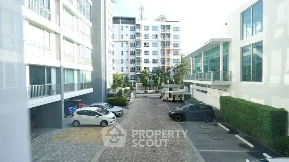 Modern apartment complex with spacious parking area and lush greenery.