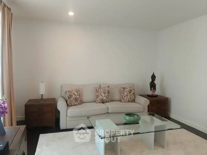 Elegant living room with cozy sofa, glass coffee table, and stylish decor accents.
