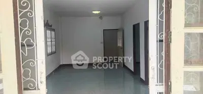 Spacious empty room with tiled floor and multiple doorways, ideal for customization.