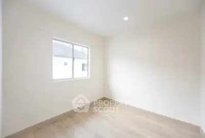 Bright empty room with wooden flooring and large window, perfect for customization.