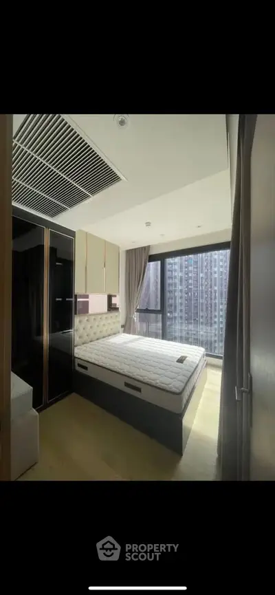 Modern bedroom with large window and city view in high-rise apartment