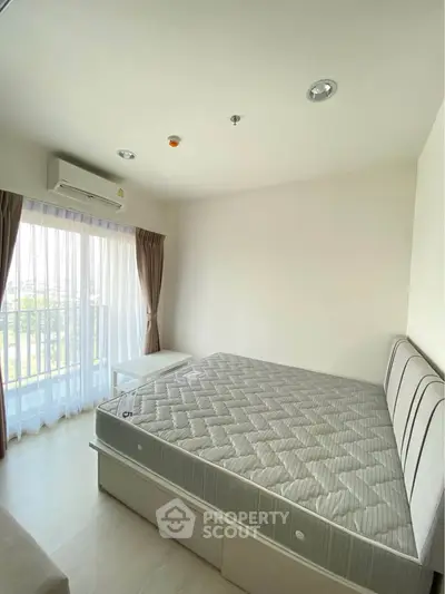Bright and airy bedroom with large window and balcony access in modern apartment.