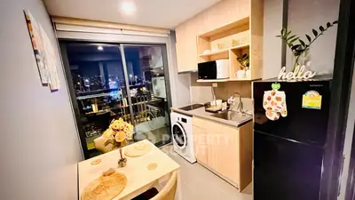 Modern kitchen with city view, featuring washing machine and dining area.