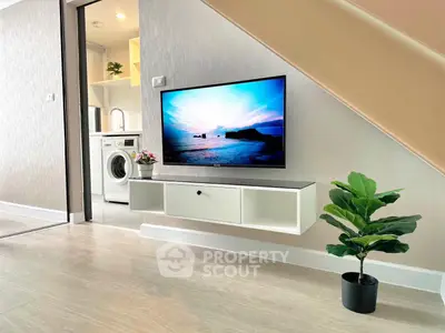 Modern living area with wall-mounted TV and washing machine under staircase
