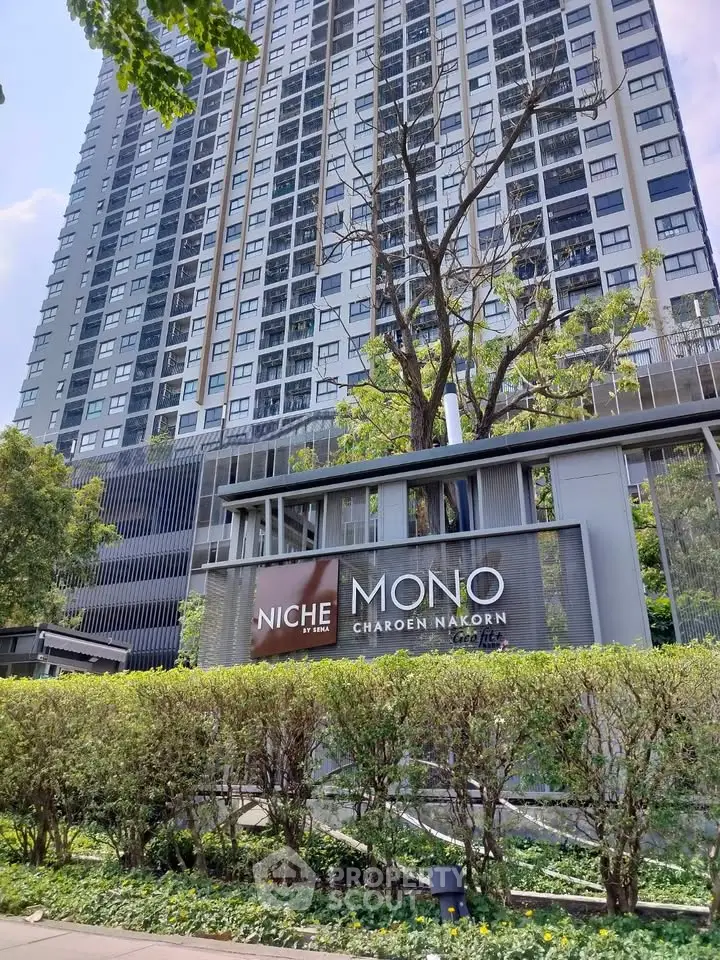 Modern high-rise condominium with lush greenery and stylish entrance signage.