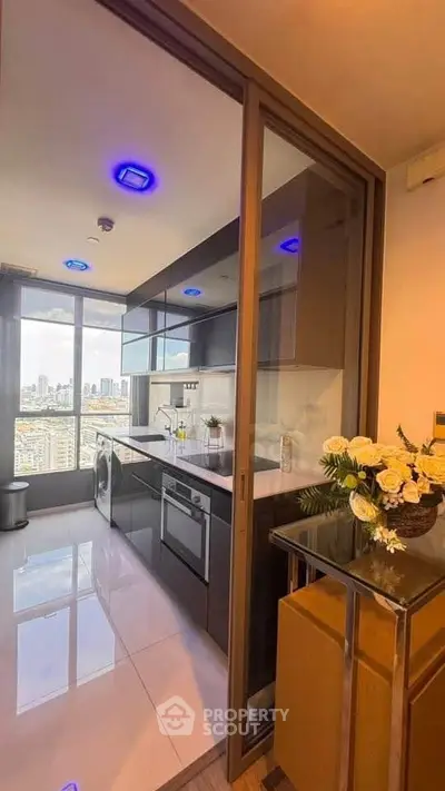 Modern kitchen with sleek design and city view, featuring built-in appliances and elegant lighting.