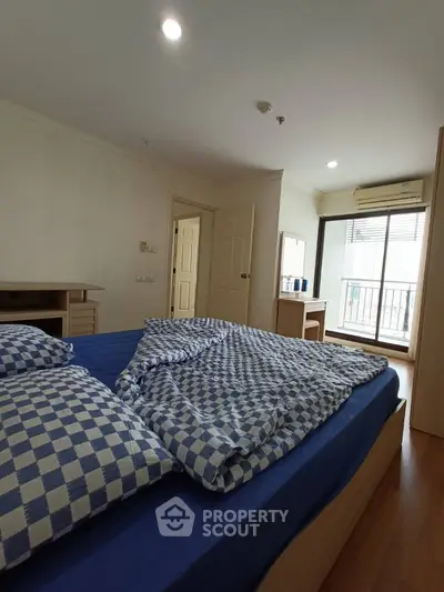 Spacious bedroom with balcony access and stylish blue checkered bedding.