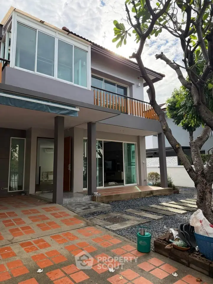 Modern two-story house with large windows and a spacious front yard, perfect for family living.