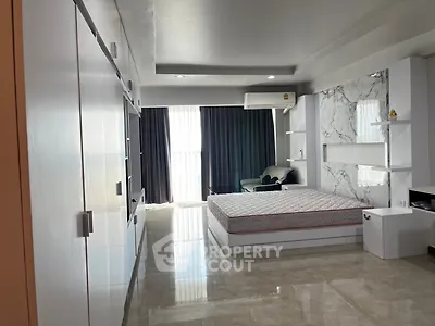 Spacious modern bedroom with marble accent wall and large windows for natural light.