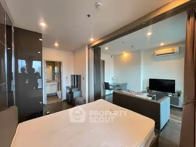 Modern studio apartment with open layout, featuring a cozy living area and bedroom separated by glass doors.