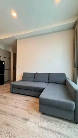 Modern living room with sleek gray sectional sofa and wooden flooring, perfect for contemporary living.