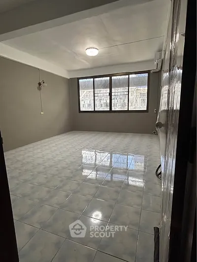 Spacious empty room with large windows and tiled flooring, perfect for customization.