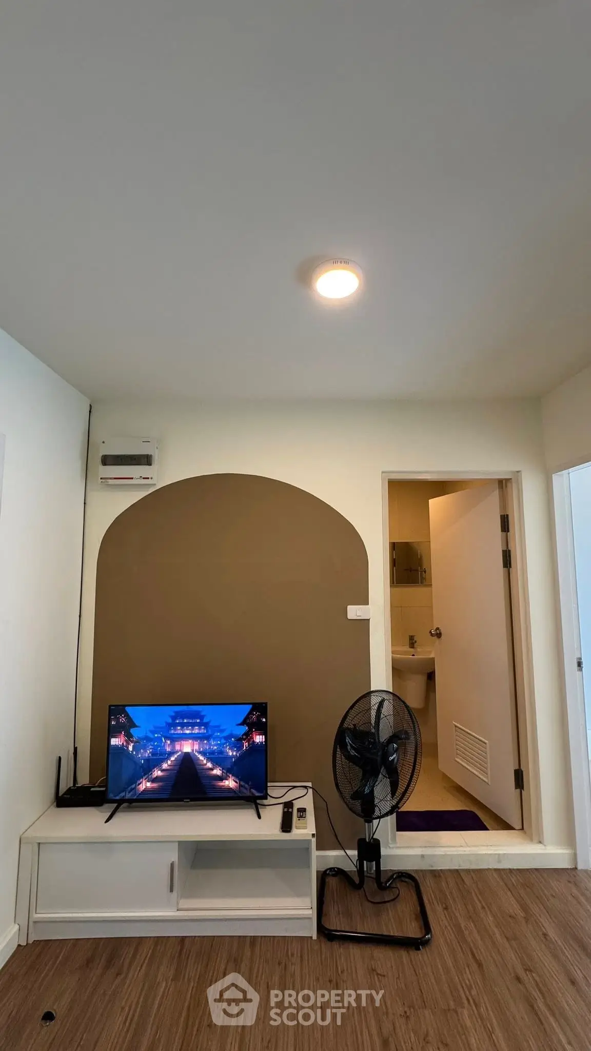 Modern living room with TV and fan, featuring a stylish arch design and wooden flooring.