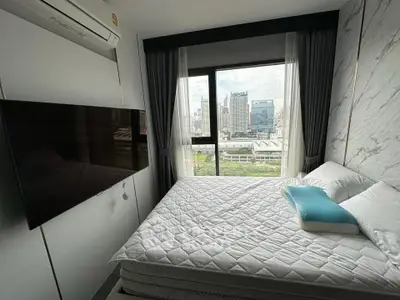 Modern bedroom with city view, featuring a large window, wall-mounted TV, and air conditioning.