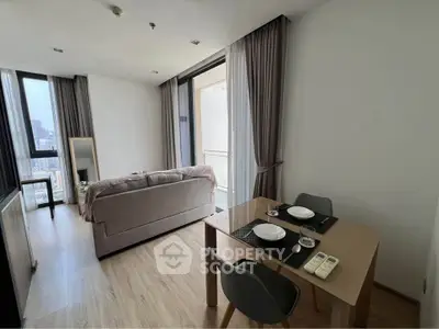 Modern living room with dining area and city view, featuring sleek furniture and floor-to-ceiling windows.