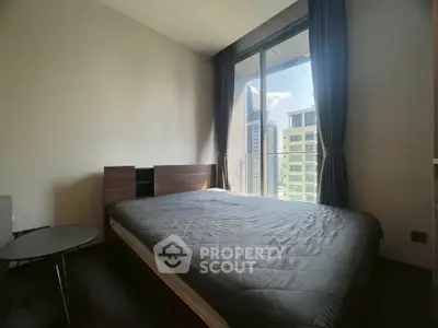 Modern bedroom with large window and city view, featuring a sleek bed and minimalist decor.