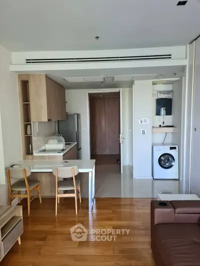 Modern open-layout kitchen with wooden flooring and built-in appliances in a cozy apartment.