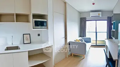 Modern living room with open kitchen, featuring a cozy sofa and large window for natural light.