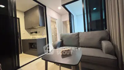 Modern living room with open kitchen in a stylish apartment, featuring sleek furniture and contemporary design.