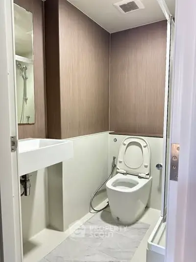 Modern compact bathroom with sleek design and neutral tones, featuring a toilet and sink.