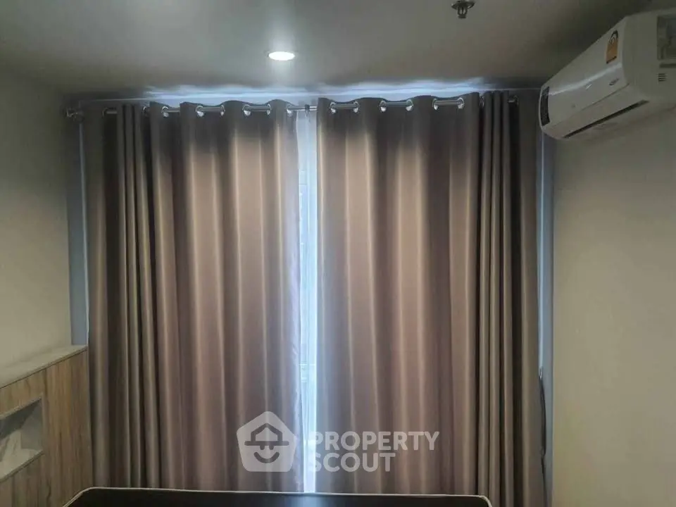 Cozy bedroom with elegant curtains and air conditioning unit, perfect for a comfortable living experience.