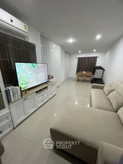 Spacious living room with modern decor and large TV, perfect for relaxation and entertainment.