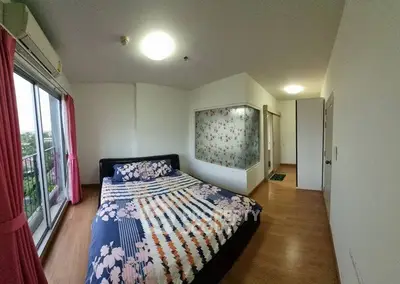 Spacious bedroom with large window and floral decor, offering a cozy and inviting atmosphere.