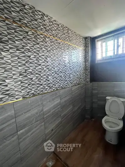 Modern bathroom with stylish geometric tiles and natural light from window.