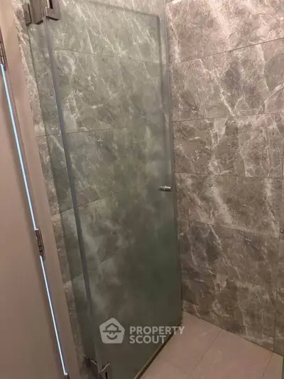 Modern bathroom with sleek glass shower door and elegant stone tile walls.