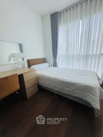 Modern bedroom with large window, elegant curtains, and stylish furniture in a bright apartment.