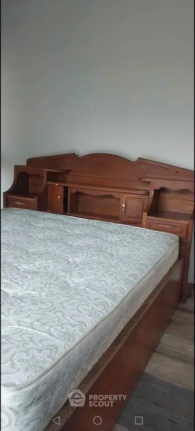 Spacious bedroom with elegant wooden bed frame and comfortable mattress, perfect for restful nights.