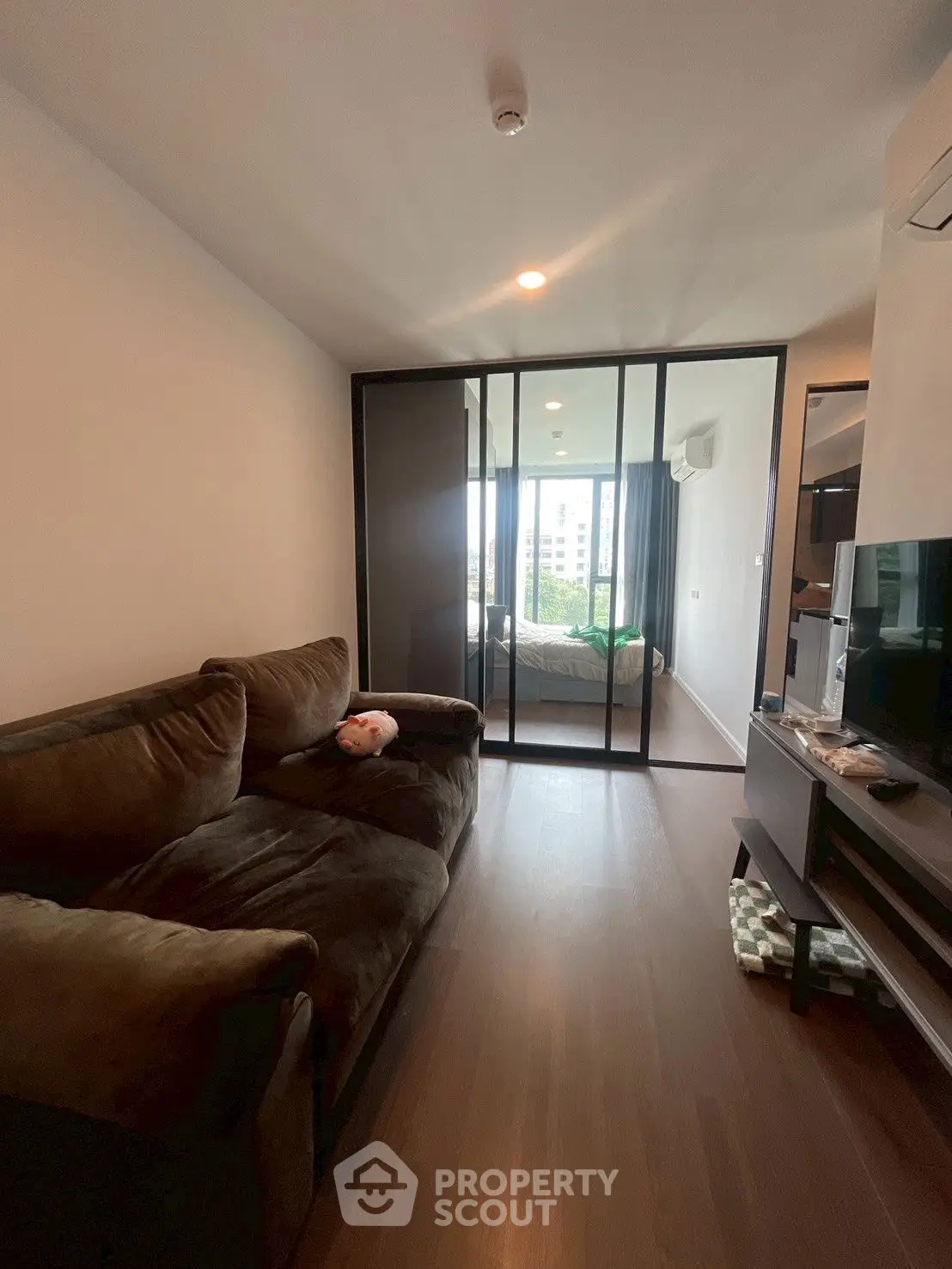 Modern apartment with cozy living room and glass partition to bedroom