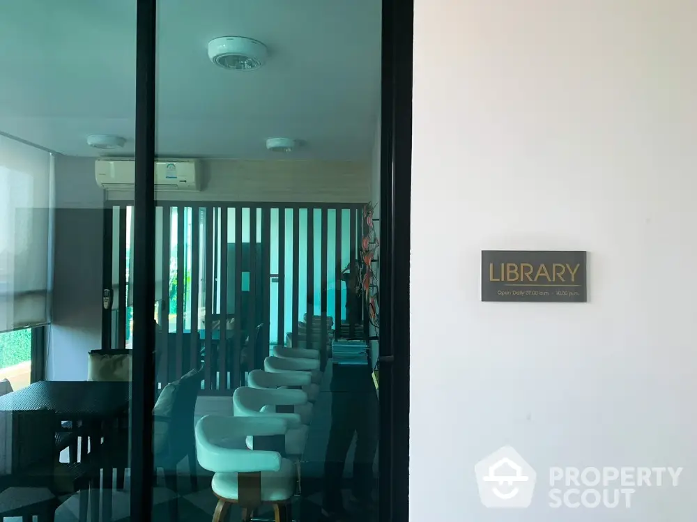 Modern library space with stylish seating and glass door entrance in a real estate property.