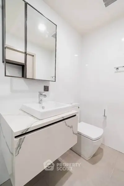 Modern minimalist bathroom with sleek white fixtures and elegant marble accents.