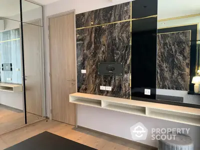 Luxurious modern living room with marble wall accents, sleek built-in shelves, and a large mirror reflecting a sophisticated interior design.