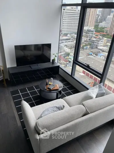 Modern living room with city view, featuring sleek furniture and large windows for natural light.