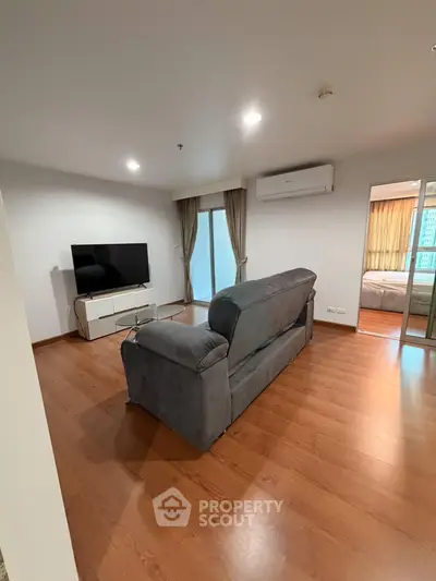 Spacious living room with modern furnishings and wooden flooring in a stylish apartment.