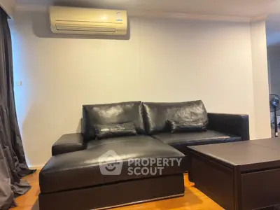 Modern living room with black leather sofa and air conditioner